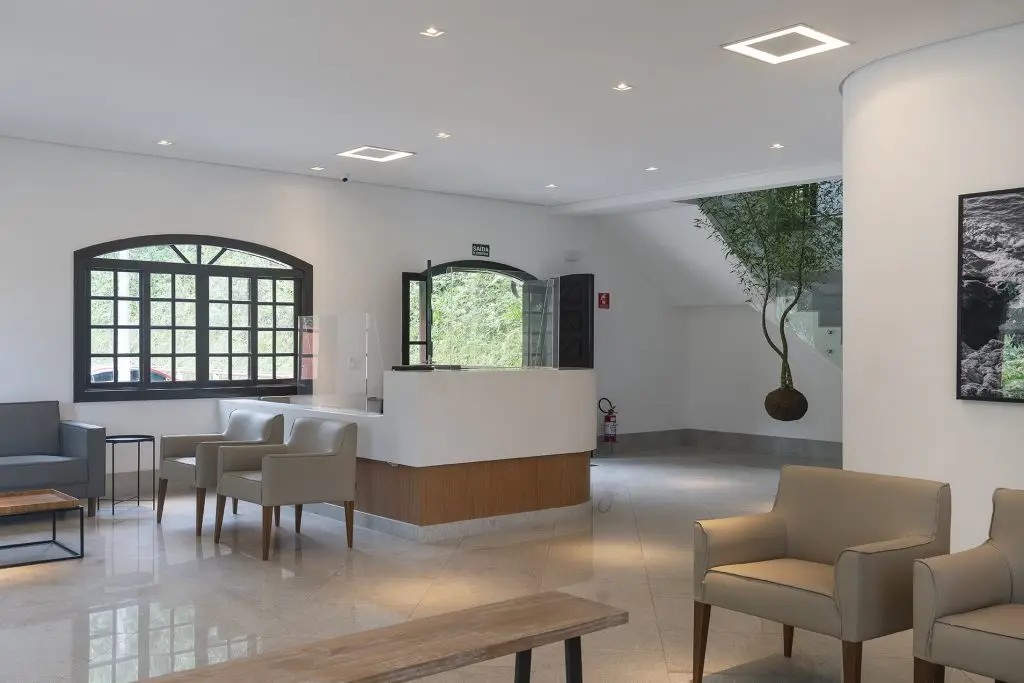 Recepção clara e acolhedora do Parque dos Ipês, com poltronas e árvore ornamental